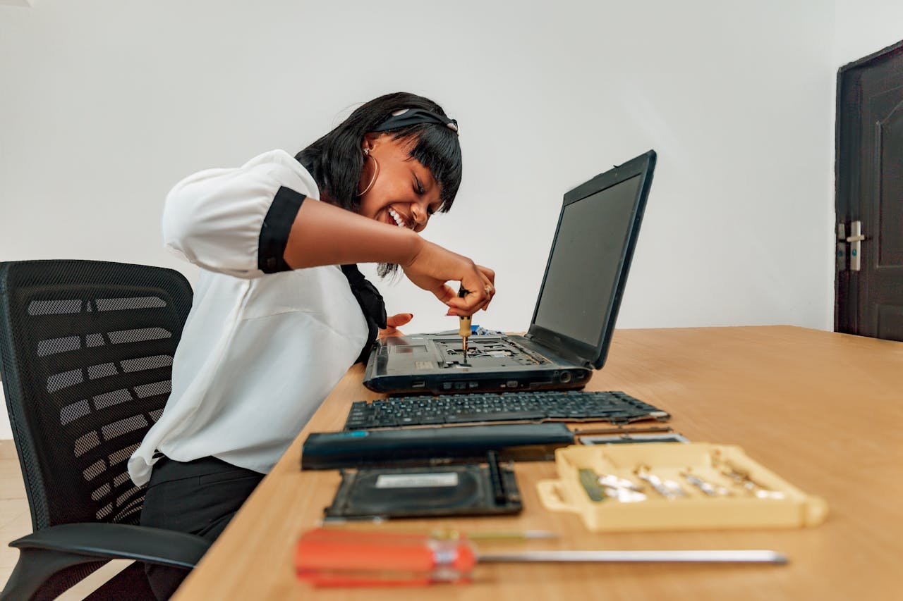 Home Woman repairing a laptop at a desk with tools, showcasing technology and skill.